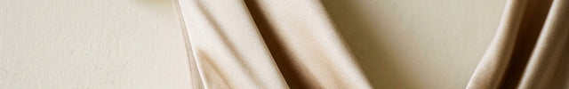 Beige sleeveless top on a brown hanger against a plain background