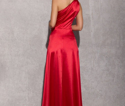 female model wearing a red satin one-shoulder bias-cut floor-length gown stands with her back turned against a grey concrete wall and floor