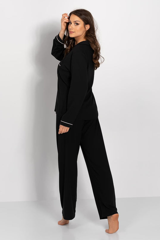 Female model wearing a black jersey long-sleeve button-front pyjama top and wide-leg bottoms in a side pose barefoot against a plain white studio background