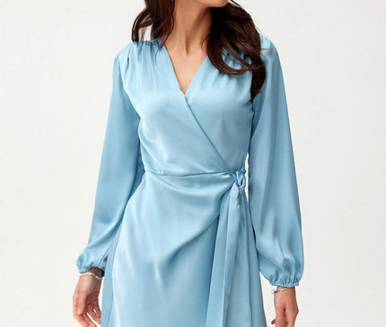 A female model stands against a plain white background wearing a light blue satin long-sleeve wrap mini dress with a V-neck and side tie looking to the side