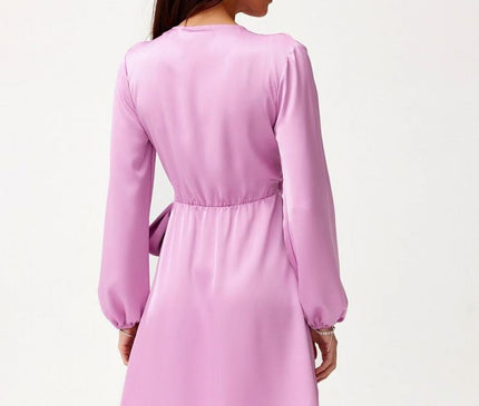 Woman model seen from the back with head in profile wearing a lilac satin long-sleeved A-line mini dress with cinched waist against a plain white background