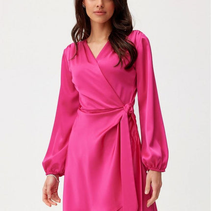 Model wearing a fuchsia satin wrap mini dress with long bishop sleeves standing against a white background