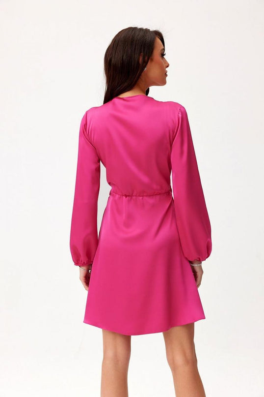 Female model stands with her back to the camera wearing a hot pink satin long-sleeve a-line mini dress with a cinched waist against a plain white background