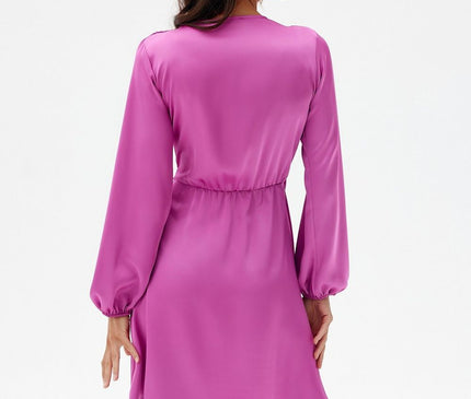 Female model stands with her back to camera wearing a fuchsia satin long-sleeve mini dress with elasticated waist against a plain white background