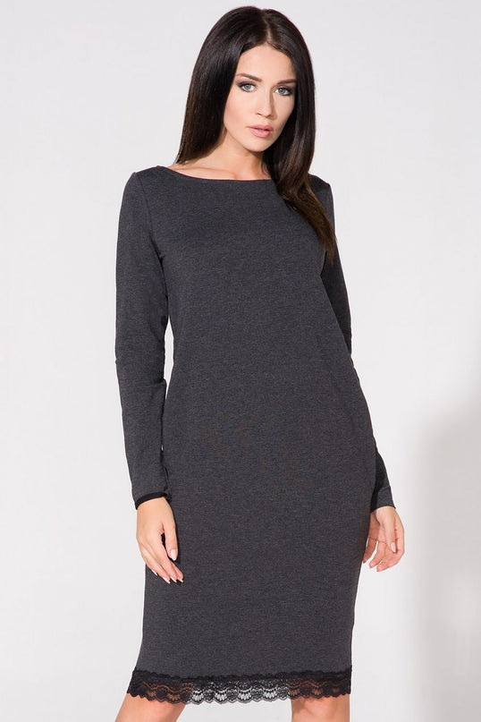 Female model in a charcoal grey knit long-sleeve straight-cut midi dress with lace trim at hem standing against a white studio background