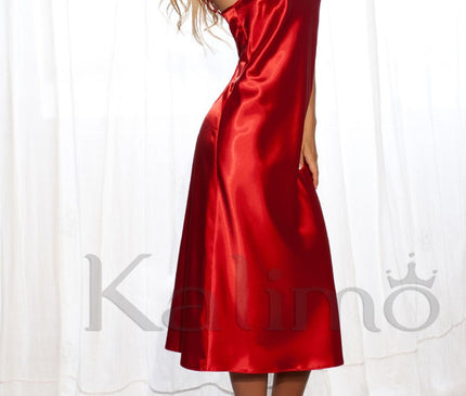 Blonde model wearing a red satin midi slip dress in a side profile pose with arms raised standing on a fluffy rug in front of sheer white curtains