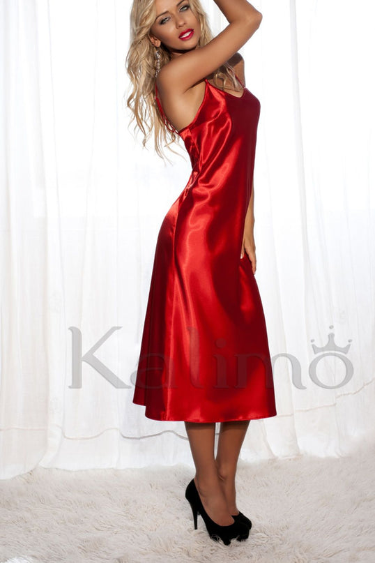 Blonde model wearing a red satin midi slip dress in a side profile pose with arms raised standing on a fluffy rug in front of sheer white curtains
