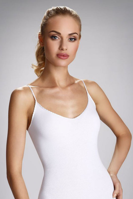 Female model facing forwards with hand on hip wearing a slim cut white ribbed stretch cotton camisole bodysuit with spaghetti straps against a plain pale grey background
