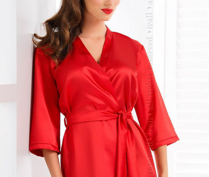 Model wearing a short red satin wrap kimono robe standing against a white wall with a shuttered window