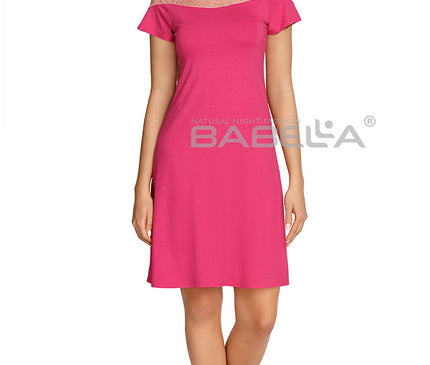 Female model standing barefoot against a white background wearing a knee-length pink jersey nightdress with a lace yoke and short sleeves