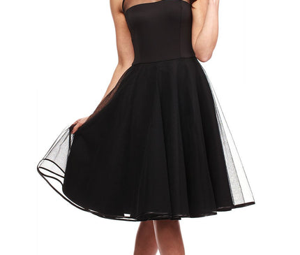 Young model wearing a black mesh yoke chiffon A-line midi dress holding the skirt with one hand against a white studio background