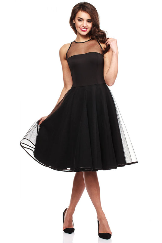 Young model wearing a black mesh yoke chiffon A-line midi dress holding the skirt with one hand against a white studio background