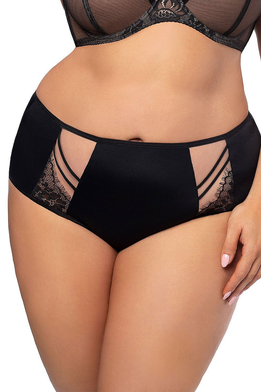 Curvy model stands against a white background wearing black high-waisted knickers in smooth fabric with sheer mesh and lace panels