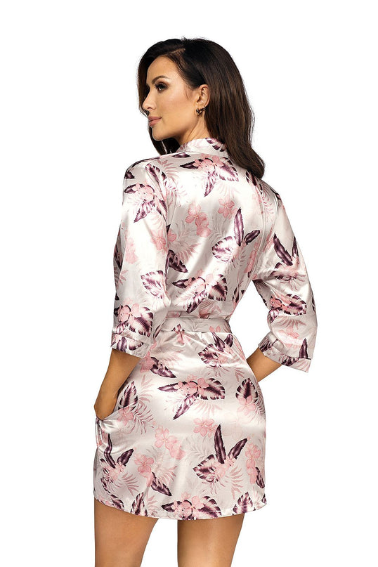 A female model in a pale pink and purple floral satin short kimono robe tied at the waist stands against a white background with her back to camera looking over her shoulder