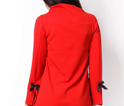 Female model turned away wearing a red crepe A-line shift dress with long sleeves and black ribbon bows on cuffs against a plain white background