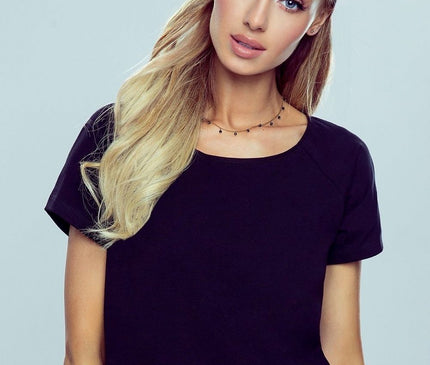 A female model poses front on with a slight head tilt against a pale grey background wearing a black cotton short sleeve crew neck t shirt in a relaxed cut