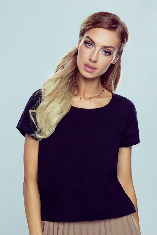 A female model poses front on with a slight head tilt against a pale grey background wearing a black cotton short sleeve crew neck t shirt in a relaxed cut