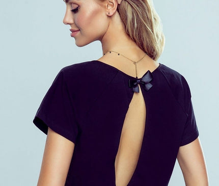 Female model wearing a black jersey short-sleeve top with a keyhole back cutout and bow detail posed in profile against a pale grey studio background