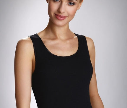 Female model wearing a black cotton scoop neck slim-fit sleeveless tank top stands with a slight head tilt and relaxed arms against a plain light grey background
