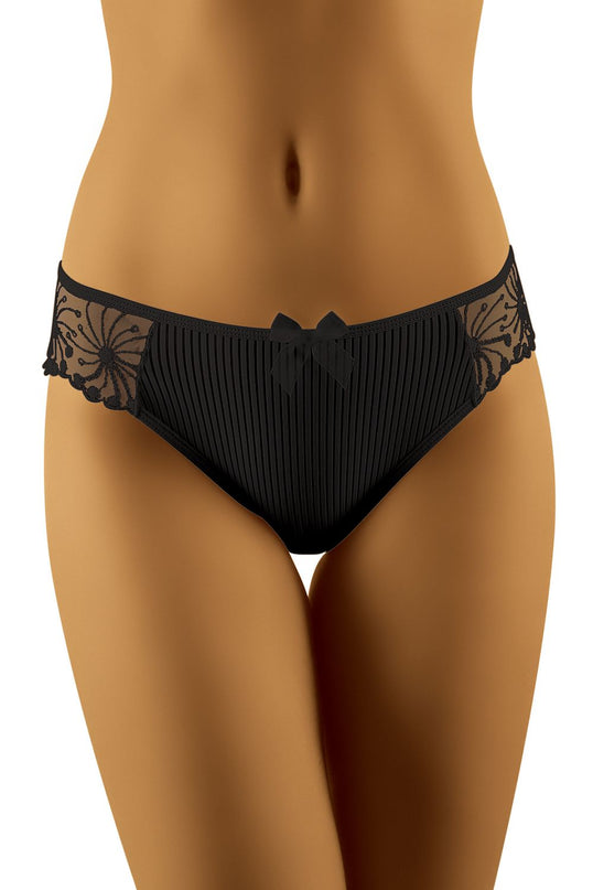 Model standing front on a white studio background wearing low-rise black pleated briefs with mesh lace side panels