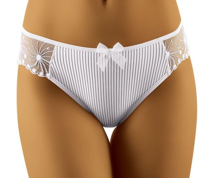 Female model wearing white ribbed fabric bikini-cut briefs with floral lace side panels and bow detail standing against a plain white background