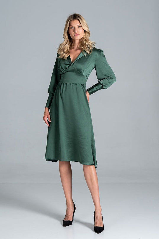 A female model posing against a plain grey background wearing a deep green satin long-sleeve V-neck midi dress with a fitted waist and flared skirt