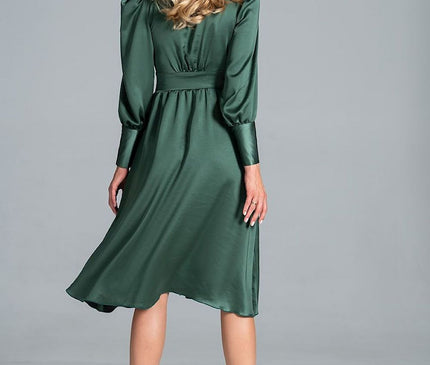 Female model standing back to camera against a grey studio backdrop wearing an emerald green satin midi dress with long sleeves, a fitted waist and a flowing skirt