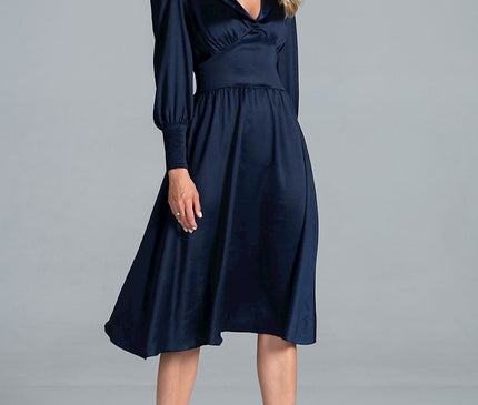 Female model standing against a plain light grey background wearing a navy satin V-neck long-sleeve midi dress with a fitted waist and flared skirt