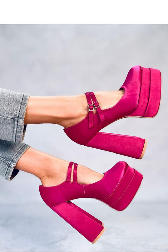 Model wearing fuchsia suede platform Mary Jane heels with double straps and chunky block heels poses with legs raised against a plain grey background