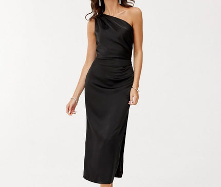 A female model stands against a plain white studio background wearing a black satin one-shoulder midi dress with a fitted cut and side slit