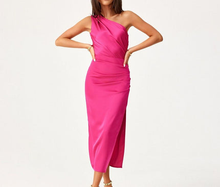 A female model stands with hands on hips wearing a hot pink satin fitted one-shoulder midi dress against a plain white studio background