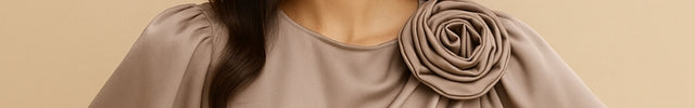 Woman wearing a beige blouse with a floral detail on a beige background