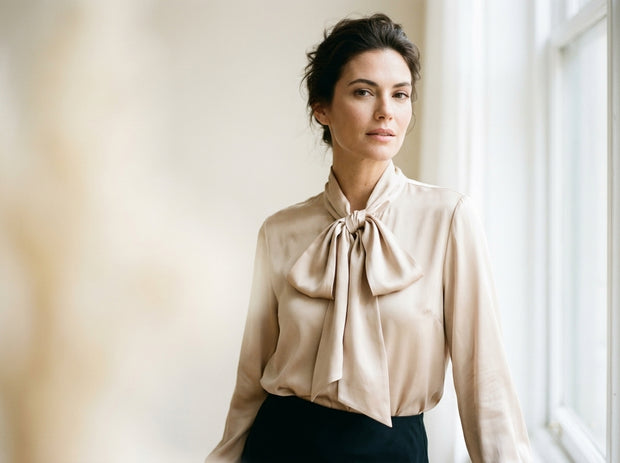 Elegant woman in a Londonian appartment wearing a beig satin shirt